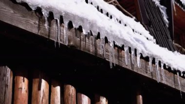 Icicles Melt and Dripping on the Sun Hanging on the Roof of Wooden House. Slow Motion