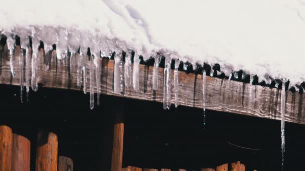 Icicles Melt and Dripping on the Sun Hanging on the Roof of Wooden House. Slow Motion — Stok video