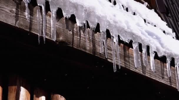 Icicles Melt and Dripping on the Sun Hanging on the Roof of Wooden House. Slow Motion — Stock video