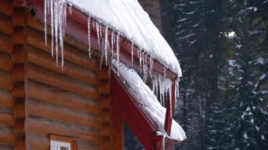 Icicles Melt and Dripping on the Sun Hanging from the Roof of Wooden House. Slow Motion