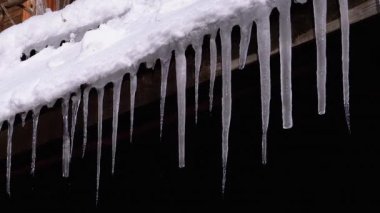 Icicles Melt and Dripping on the Sun Hanging on the Roof of Wooden House. Slow Motion