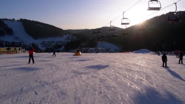 Lyžaři a snowboardisté Jízda na zasněženém svahu v lyžařském středisku ve slunečný den — Stock video