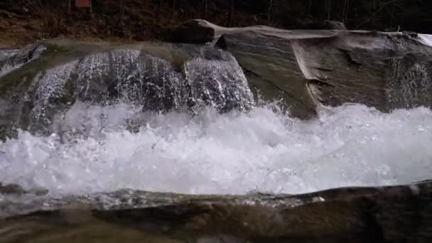 Горный ручей и каменные пороги со снегом. Быстрый поток воды. Зимний водопад. Slow Motion — стоковое видео