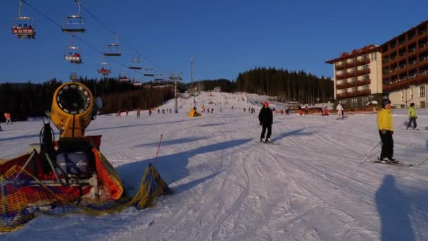 Skidåkare och snowboardåkare Rider på en snöig backe på en skidort på soliga dagen — Stockvideo