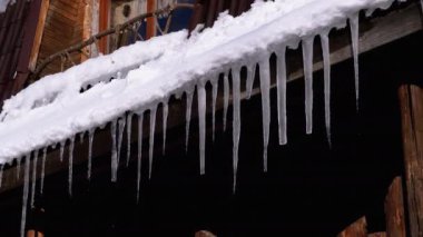 Icicles Melt and Dripping on the Sun Hanging on the Roof of Wooden House. Slow Motion