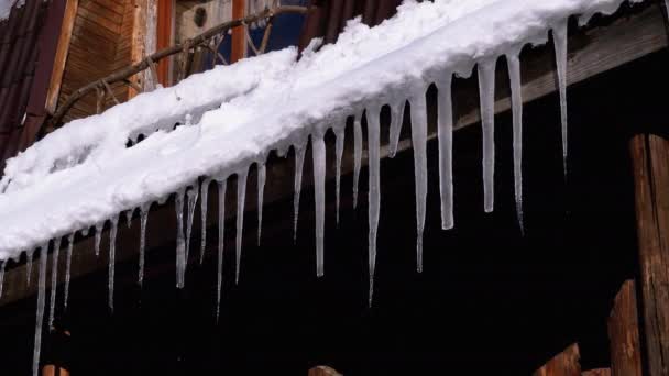 Icicles Melt and Dripping on the Sun Hanging on the Roof of Wooden House. Slow Motion — Stock Video