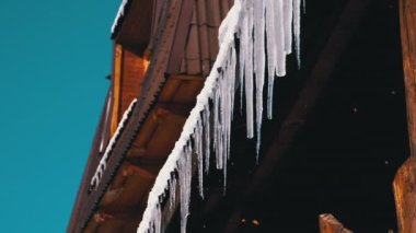 Icicles Melt and Dripping on the Sun Hanging on the Roof of Wooden House. Slow Motion