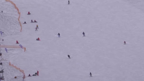 Esquiadores e snowboarders passeio em uma encosta nevada em uma estância de esqui em dia ensolarado — Vídeo de Stock