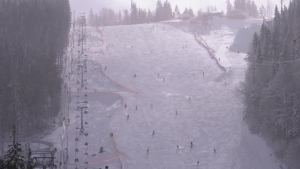 Esquiadores e snowboarders passeio em uma encosta nevada em uma estância de esqui em dia ensolarado — Vídeo de Stock