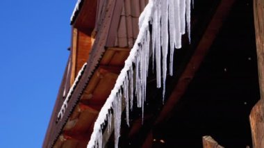 Icicles Melt and Dripping on the Sun Hanging from the Roof of Wooden House. Slow Motion