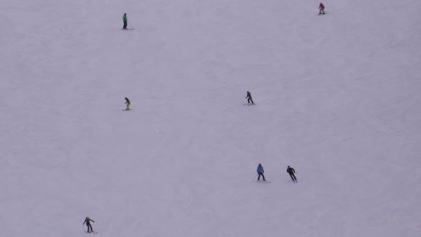 Лижники і сноубордисти їдуть на сніговому схилі на лижному курорті в сонячний день. — стокове відео