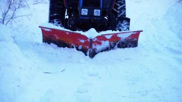 Traktor Plow rensar snö på en väg i skogen. Snöskottning — Stockvideo