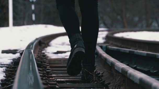 Pernas de uma menina Caminhando ao longo das trilhas ferroviárias antigas no inverno. Movimento lento — Vídeo de Stock