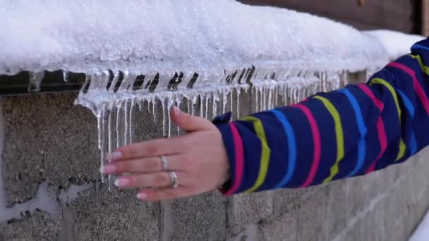 Meisje klopt ijspegels door haar hand op een winterdag. Slow Motion. IJsjes verwijderen — Stockvideo