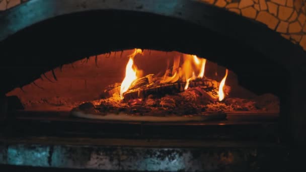 Cocinar pizza en un horno de arcilla a leña italiano en un restaurante — Vídeo de stock