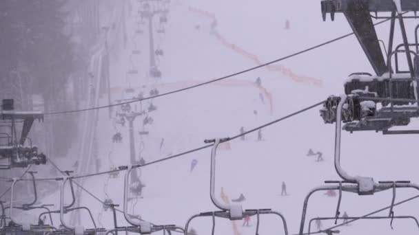 Remonte en la estación de esquí. Esquiadores suben a un elevador de la silla de esquí hasta la pista de esquí con nieve cayendo — Vídeos de Stock