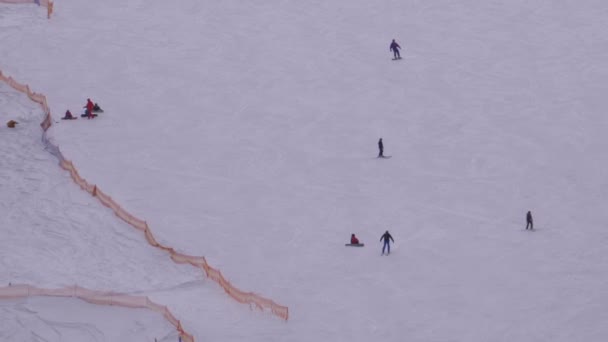 Esquiadores e snowboarders passeio em uma encosta nevada em uma estância de esqui em dia ensolarado — Vídeo de Stock