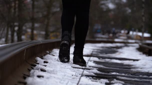 Jambes d'une fille marchant le long des anciennes voies ferrées en hiver. Mouvement lent — Video