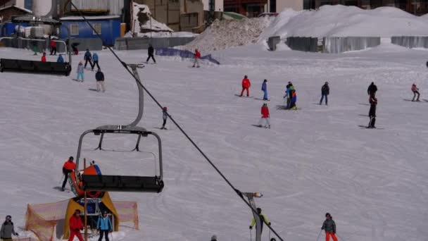 Les skieurs et les snowboarders montent sur une piste enneigée dans une station de ski — Video