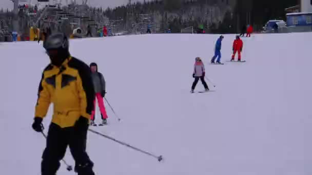 Esquiadores e snowboarders passeio em uma encosta nevada em uma estância de esqui em dia ensolarado — Vídeo de Stock