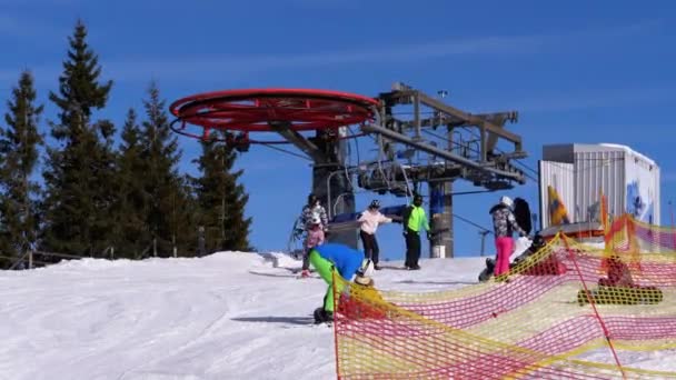 Skidlift med skidåkare på skidorten. Skidåkare stiger ner från liften vid Upper Station — Stockvideo