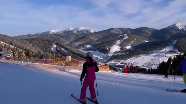 Lyžaři a snowboardisté Jízda v horách na zasněženém svahu v lyžařském středisku ve slunečný den — Stock video