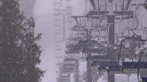 Remontées mécaniques sur la station de ski. Les skieurs grimpent sur une chaise de ski Ascenseur jusqu'à la piste de ski avec chute de neige — Video