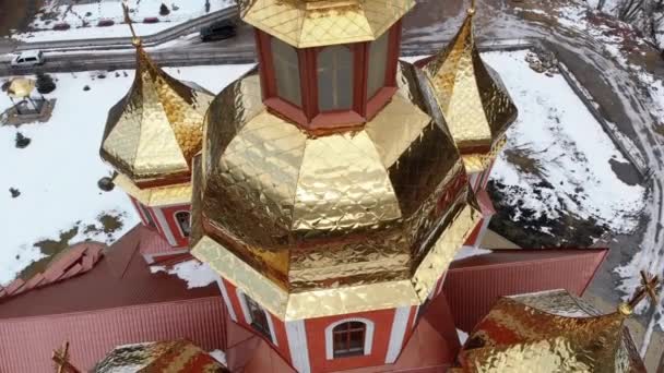 Вид с воздуха на Украинскую Церковь с золотыми куполами в Карпатской деревне зимой — стоковое видео