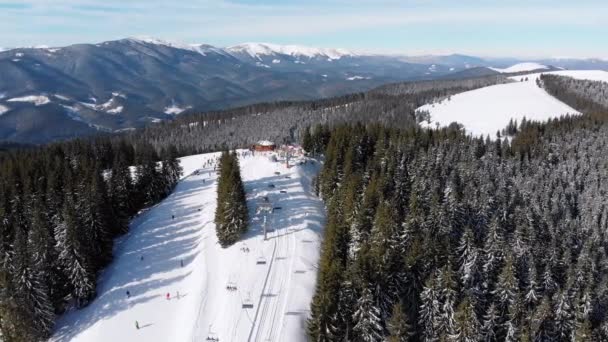 Piste da sci aeree con sciatori e impianti di risalita sulla stazione sciistica. Foresta montana innevata — Video Stock