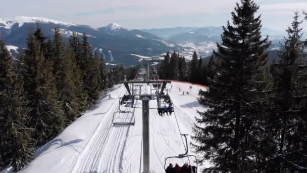 Drone vola sopra gli impianti di risalita e pista da sci innevata con sciatori in cima alla montagna — Video Stock