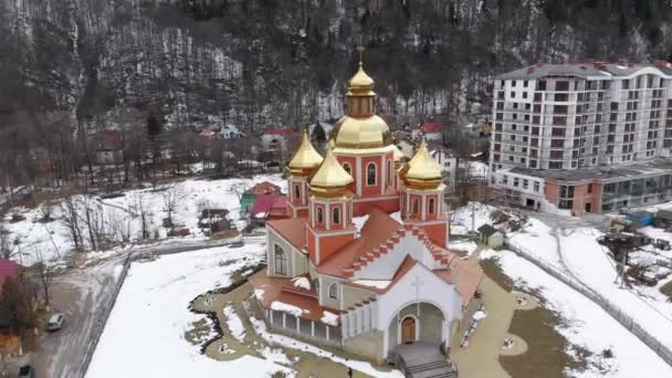 Letecký pohled na ukrajinský kostel se zlatými kopulemi v Karpatské vesnici v zimě — Stock video