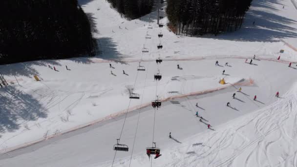 Вид с воздуха на горнолыжные склоны с лыжниками спускается под подъемники на горнолыжном курорте — стоковое видео