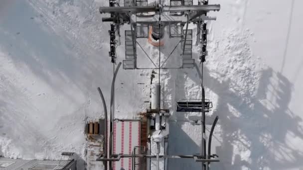 Vista aerea dall'alto dell'impianto di risalita per gli sciatori da trasporto sulla pista da sci innevata. Drone vola sopra la sedia ascensore — Video Stock