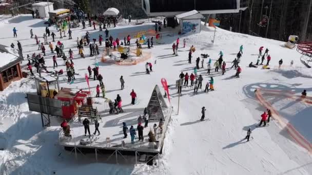 Вид с воздуха Толпа лыжников, катающихся на лыжном склоне у подъемников. Горнолыжный курорт — стоковое видео