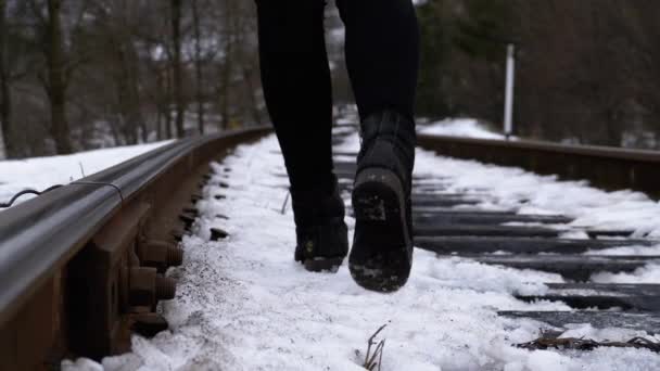Ноги девушки, идущей по старым железнодорожным путям зимой. Slow Motion — стоковое видео
