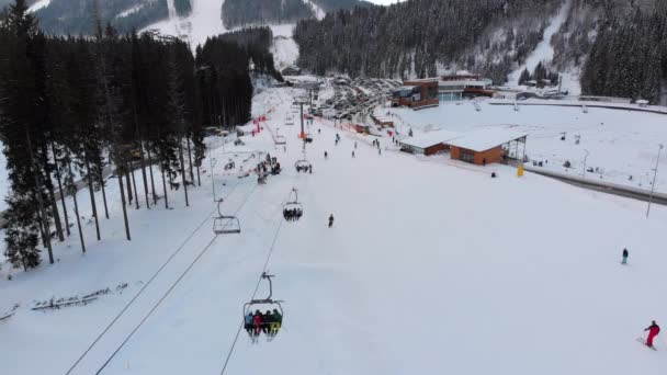 Вид с воздуха на горнолыжный курорт с парковкой для автомобилей. Горнолыжные трассы и подъемники зимой — стоковое видео