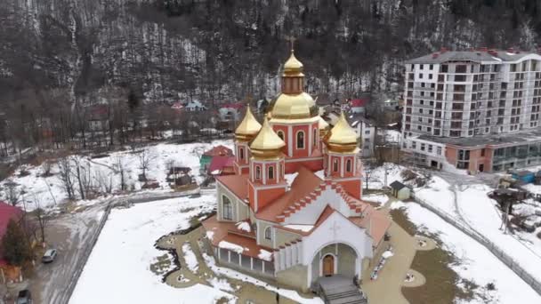 Vista aérea de la iglesia ucraniana con cúpulas de oro en la aldea de los Cárpatos en invierno — Vídeo de stock