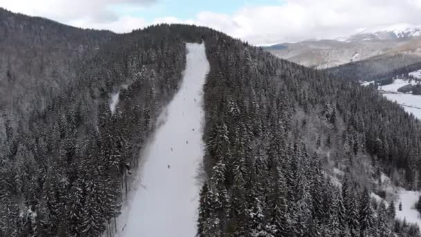 Inclinações aéreas de esqui com esquiadores no Ski Resort. Floresta de abeto de montanha nevada. Bukovel. — Vídeo de Stock