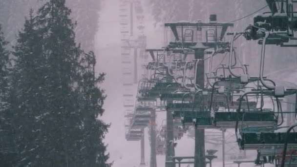 Elevador de esqui no Ski Resort, câmera lenta. Esquiadores Suba na cadeira de esqui Elevador para Ski Slope com queda de neve — Vídeo de Stock