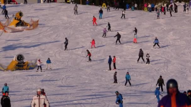 Σκιέρ και snowboarders βόλτα σε μια χιονισμένη πλαγιά σε ένα χιονοδρομικό κέντρο στην ηλιόλουστη μέρα — Αρχείο Βίντεο