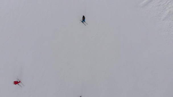 Luchtfoto Bovenaanzicht van skiërs gaan de skipiste op skigebied in bergen af — Stockvideo