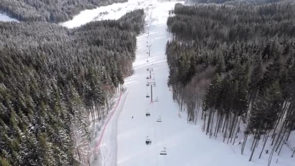 Vista aérea dos esquiadores descem pistas de esqui perto de teleféricos na estação de esqui. Bukovel. — Vídeo de Stock