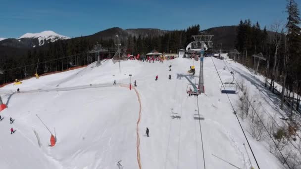 Vista aérea de las pistas de esquí con esquiadores bajan bajo remontes en la estación de esquí — Vídeos de Stock