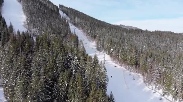 Letecký pohled na lyžaře sjíždějí sjezdovky v blízkosti lyžařských vleků na lyžařském středisku. Bukovel — Stock video