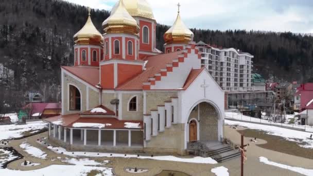 Vista aérea de la iglesia ucraniana con cúpulas de oro en la aldea de los Cárpatos en invierno — Vídeo de stock