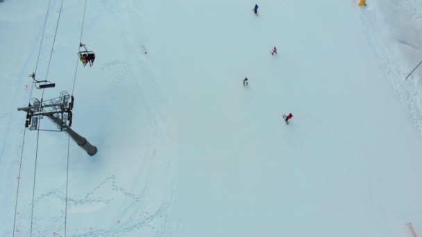 Top Aerial view of Skiers Slide Down the Ski Slope and Ski Chair Lift on Ski Resort in Winter — ストック動画