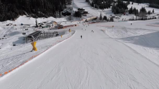 Вид с воздуха Множество лыжников спускаются по лыжным склонам. Беспилотники летают рядом с беспилотниками — стоковое видео