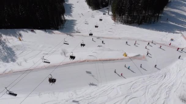 Vista aérea de las pistas de esquí con esquiadores bajan bajo remontes en la estación de esquí — Vídeos de Stock