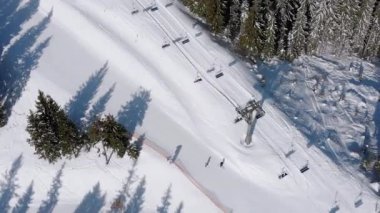 Aerial view of Ski Slopes with Skiers go Down under Ski Lifts on Ski Resort