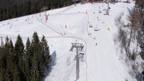 Vista aérea de las pistas de esquí con esquiadores bajan bajo remontes en la estación de esquí — Vídeo de stock